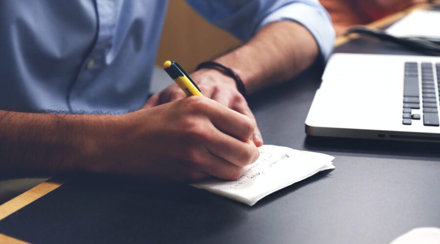 Free Person Writing on Paper Using Yellow and Black Pen Stock Photo