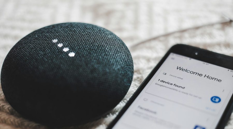 Turned-on charcoal Google Home Mini and smartphone photo