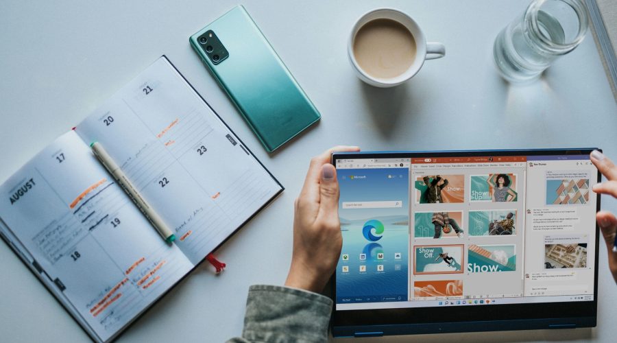 person using Windows 11 computer beside white ceramic mug on white table