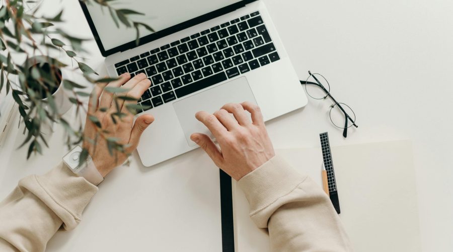 Free An overhead view of a person working on a laptop in a minimalist home office setting. Stock Photo