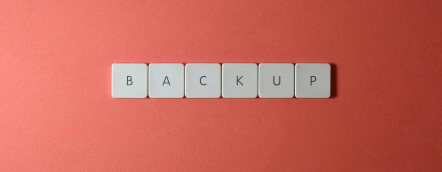 Free Close-up of keyboard keys spelling 'BACKUP' placed on a coral-colored surface. Stock Photo