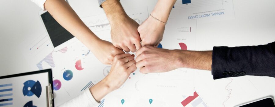 Free Colleagues celebrate success with a fist bump over financial charts depicting teamwork and unity. Stock Photo