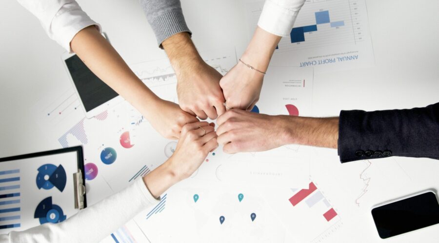 Free Colleagues celebrate success with a fist bump over financial charts depicting teamwork and unity. Stock Photo
