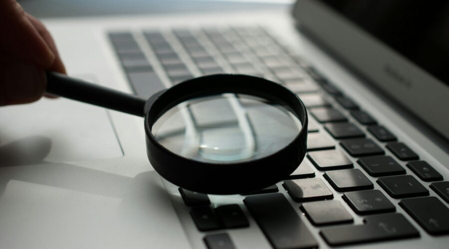 magnifying glass near gray laptop computer