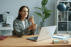 lady holding phone while working on a laptop