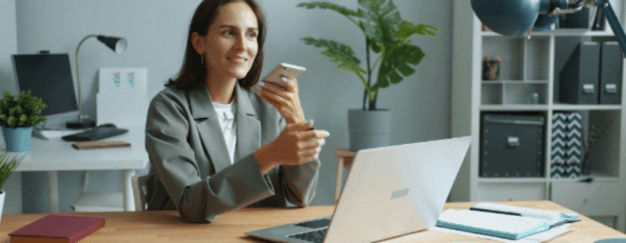 lady holding phone while working on a laptop